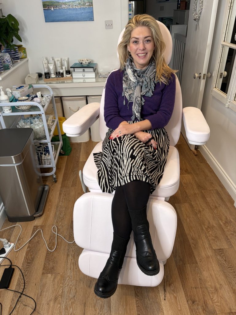 Dr Amber Halliday seated comfortably in the Blue Bird Aesthetics treatment room, showing the calm, professional environment where doctor‑led aesthetic treatments take place