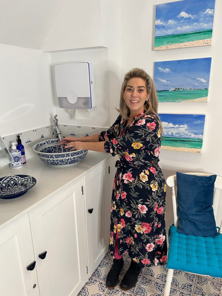 Dr Halliday inside the clinic room using the sink at Blue Bird Aesthetics in Worthing