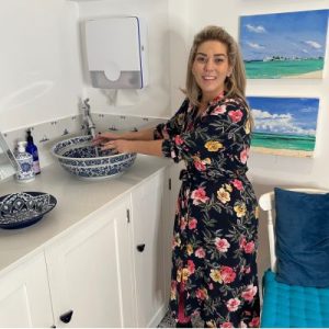 Dr Halliday inside the clinic room using the sink at Blue Bird Aesthetics in Worthing