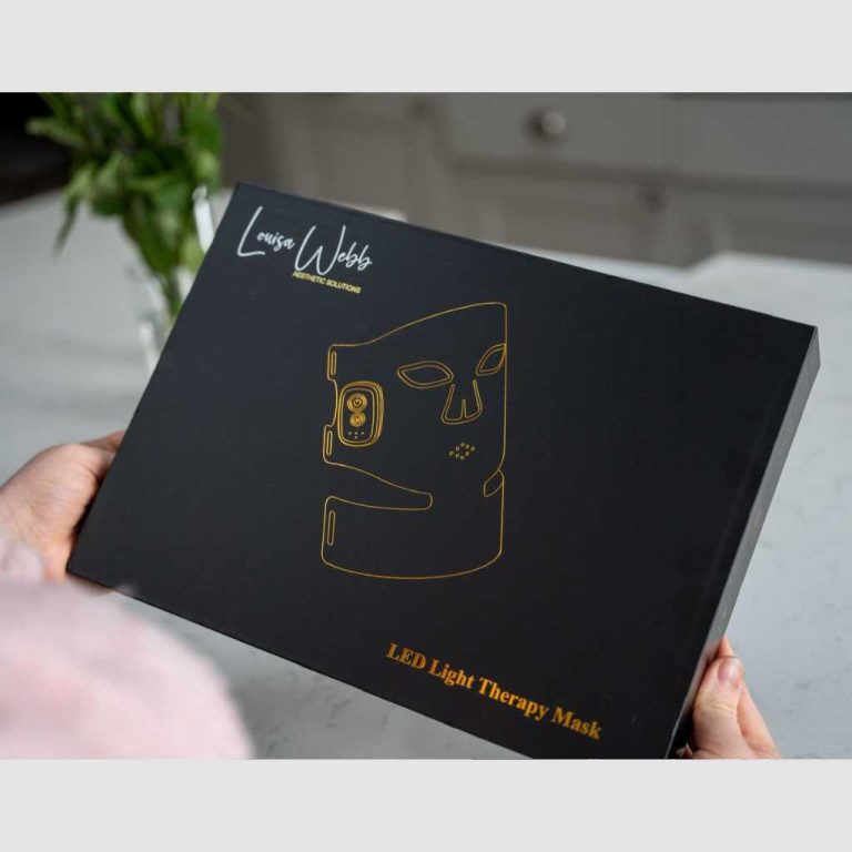 Black LW Aesthetic Solutions LED Light Therapy Mask box held in two hands, featuring gold line art of the mask on the front.